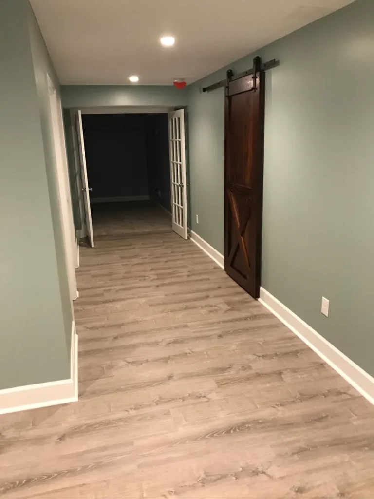 Finished basement hallway with barn door and French doors by Edges Unlimited in Clifton Park, NY