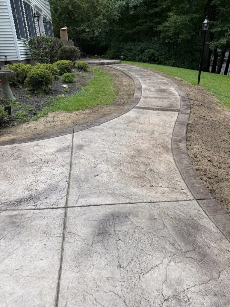 Resealed curved stamped concrete walkway with border by Edges Unlimited in Clifton Park, NY