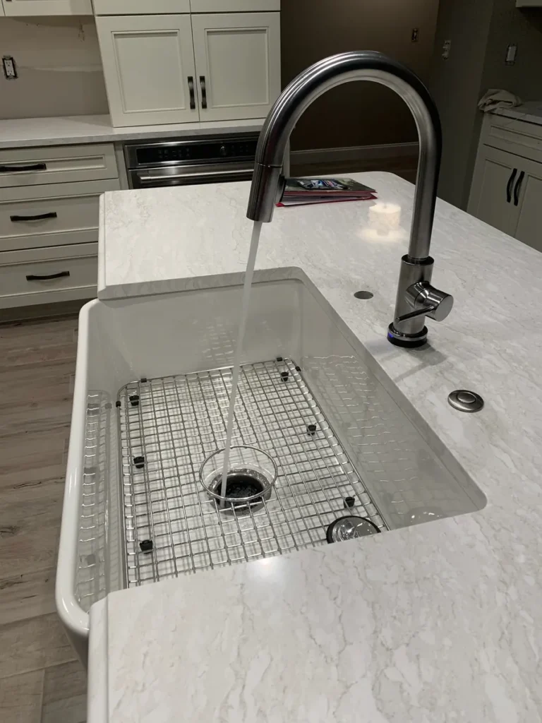 Farmhouse sink and quartz island in a remodeled kitchen by Edges Unlimited in Clifton Park, NY