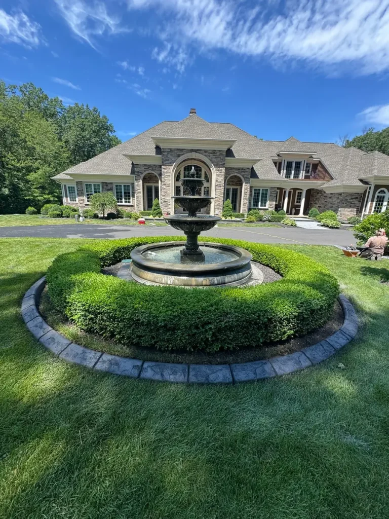 Circular concrete curbing around a fountain and boxwoods by Edges Unlimited in Clifton Park, NY