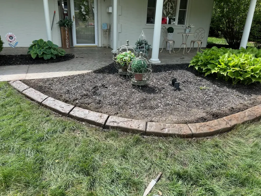 Concrete landscape curbing along a front porch mulch bed by Edges Unlimited in Clifton Park, NY