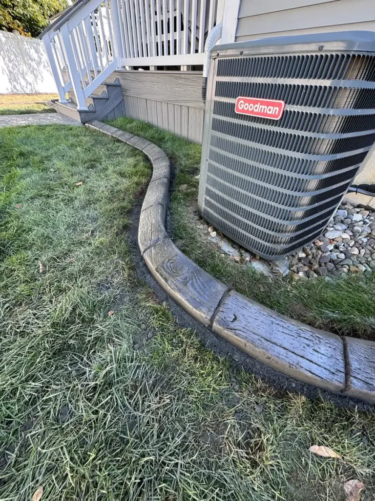 Wood grain stamped landscape curbing around an AC unit by Edges Unlimited in Clifton Park, NY