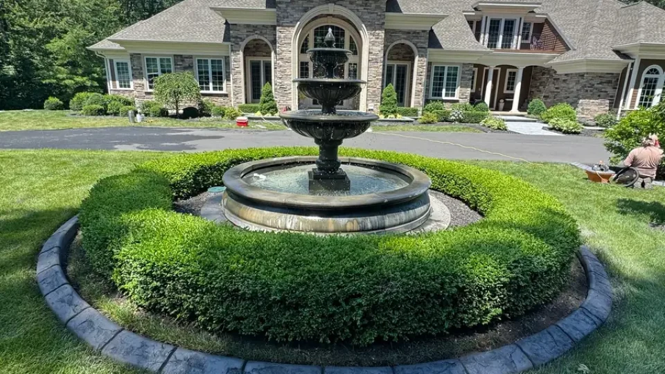 Circular concrete curbing around a fountain and boxwoods by Edges Unlimited in Clifton Park, NY