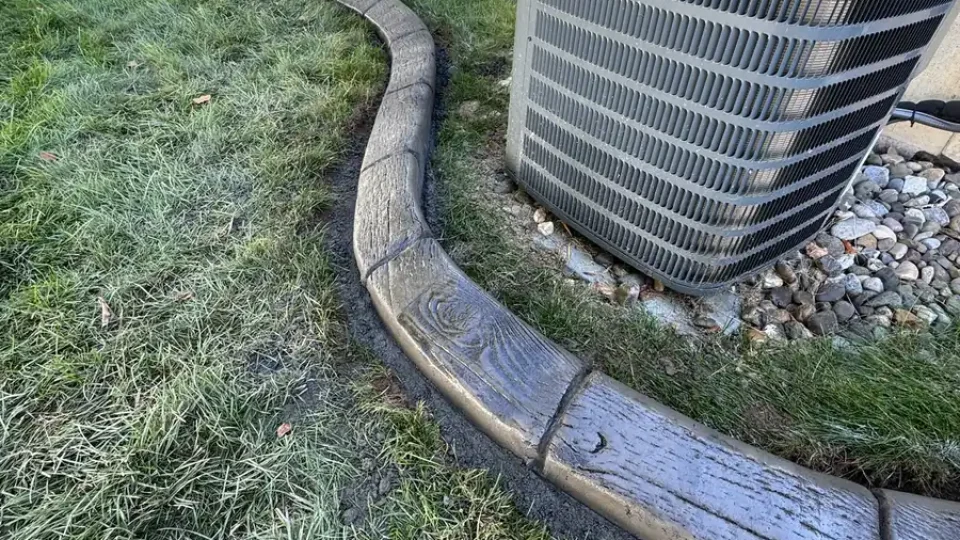 Wood grain stamped landscape curbing around an AC unit by Edges Unlimited in Clifton Park, NY