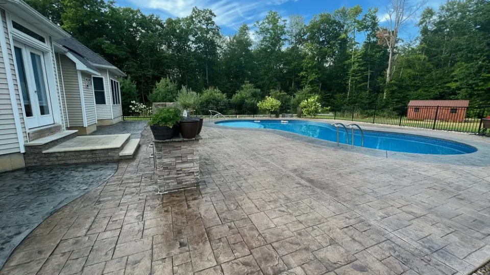 Stamped concrete pool deck with an aluminum fence by Edges Unlimited in Latham, NY